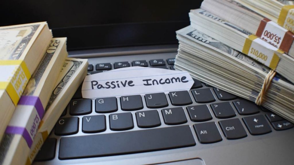image of stack of money on computer with passive income paper
