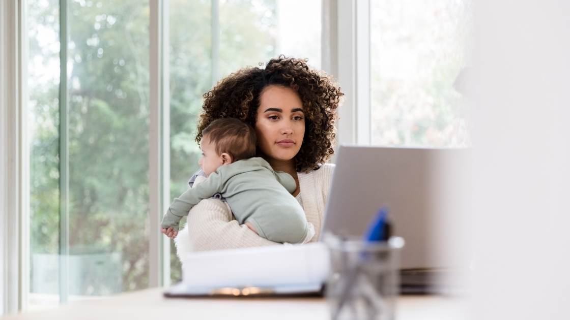 how can i make money as a stay at home mom image of mom holding baby in front of computer