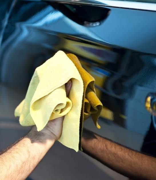 how to start a waterless car wash image of man washing car with towel
